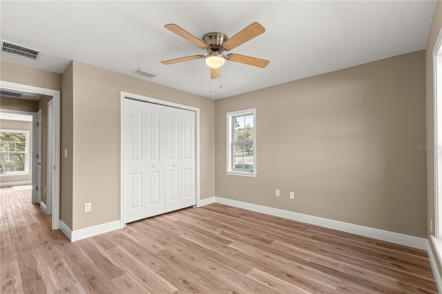 unfurnished bedroom with light wood-style floors, visible vents, and multiple windows