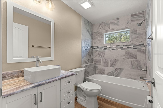 bathroom featuring visible vents, toilet, wood finished floors, vanity, and washtub / shower combination