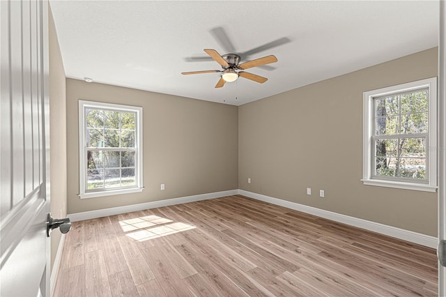 empty room with light wood-style flooring, baseboards, ceiling fan, and a textured ceiling