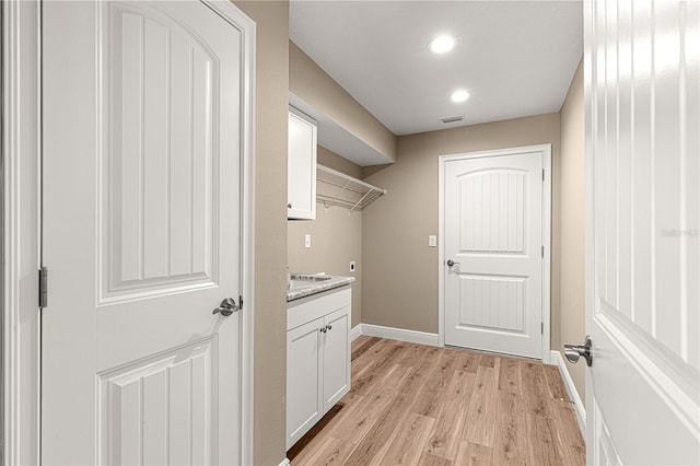 washroom featuring light wood finished floors, cabinet space, baseboards, visible vents, and hookup for an electric dryer