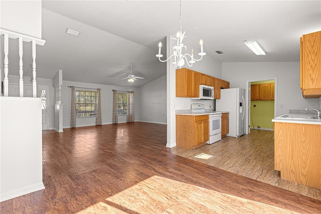 kitchen featuring white appliances, light countertops, open floor plan, and ceiling fan with notable chandelier