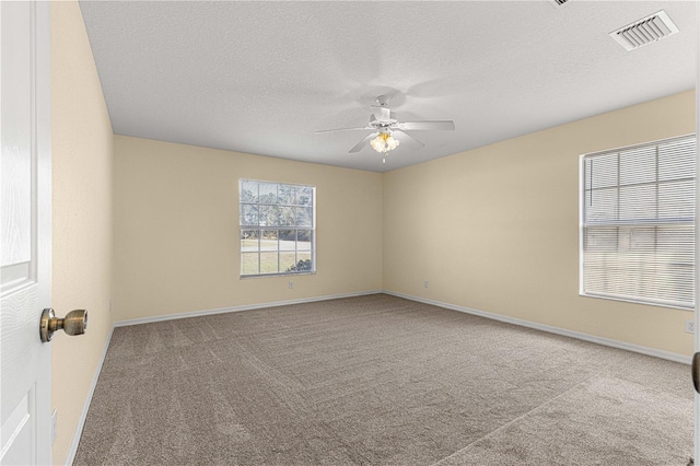 carpeted empty room with baseboards, ceiling fan, visible vents, and a textured ceiling