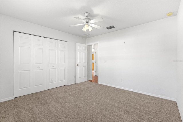 unfurnished bedroom featuring carpet, a closet, visible vents, a ceiling fan, and baseboards