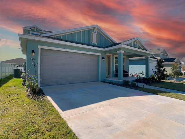 view of front of house featuring central AC unit, a lawn, concrete driveway, fence, and board and batten siding