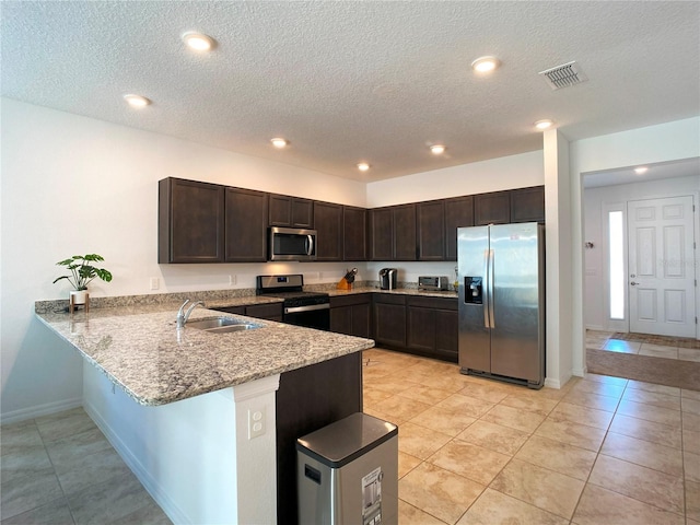 kitchen with visible vents, appliances with stainless steel finishes, a sink, dark brown cabinetry, and a peninsula