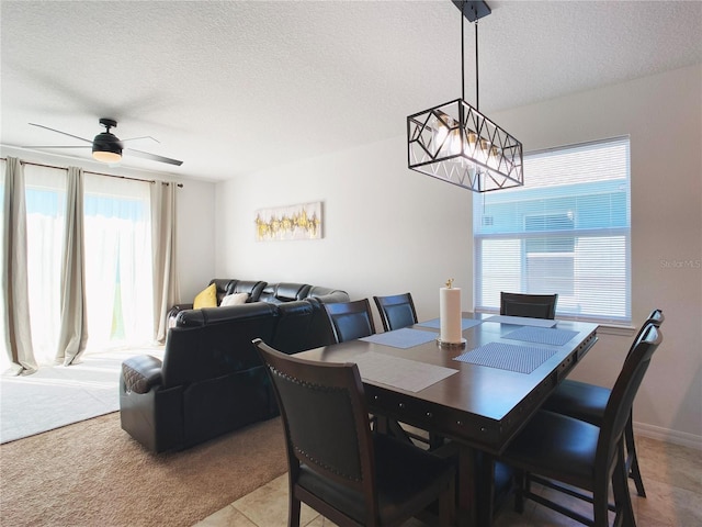 dining area with light carpet, ceiling fan, baseboards, and a textured ceiling