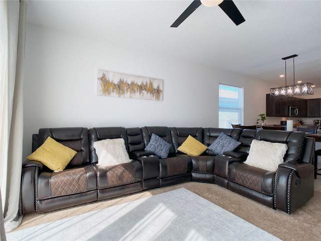 living area featuring light carpet and ceiling fan with notable chandelier