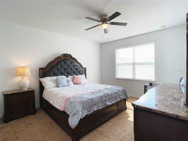 bedroom featuring ceiling fan, baseboards, a textured ceiling, and light colored carpet