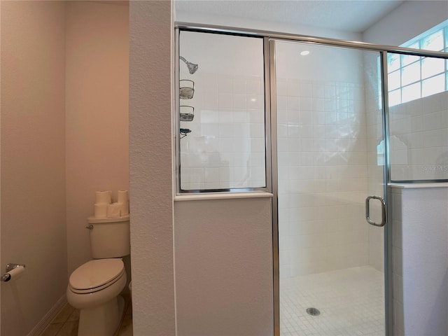 full bath featuring baseboards, a shower stall, toilet, and tile patterned floors