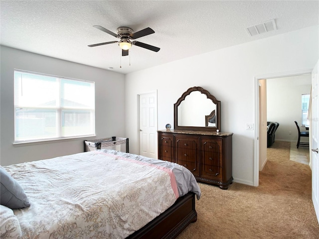 bedroom with light carpet, baseboards, visible vents, and a textured ceiling