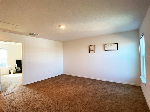 unfurnished room featuring a textured ceiling, dark carpet, visible vents, and baseboards