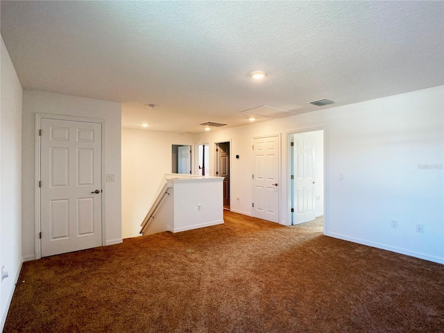 unfurnished room with a textured ceiling, carpet floors, and visible vents