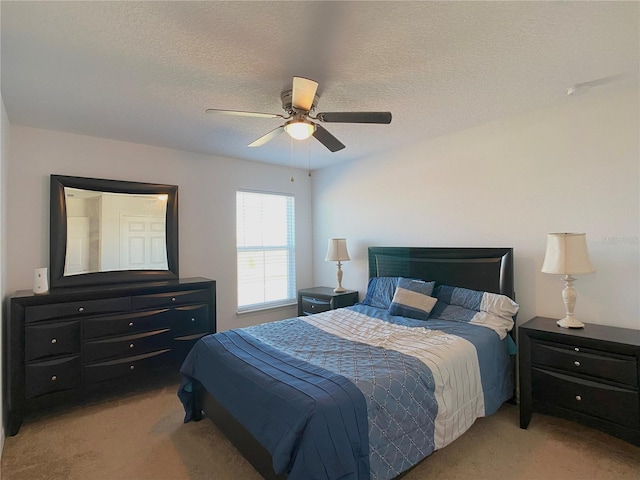 bedroom with light carpet, a ceiling fan, and a textured ceiling