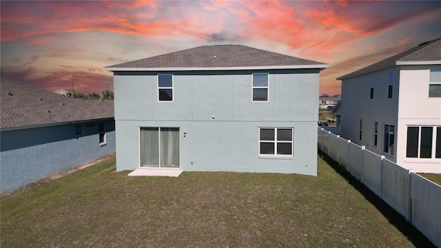 back of property featuring a lawn, fence, and stucco siding