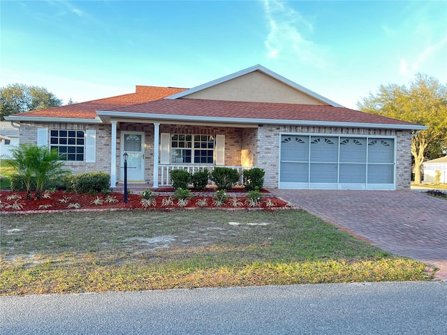 ranch-style house with roof with shingles, an attached garage, decorative driveway, a porch, and brick siding