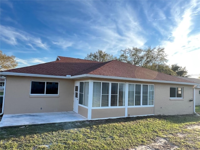 rear view of property with a yard, a patio area, roof with shingles, and stucco siding