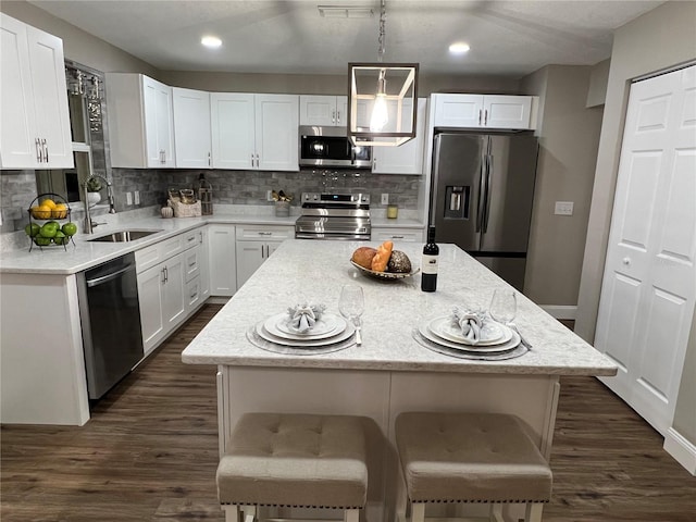 kitchen with white cabinets, stainless steel appliances, a sink, and a center island