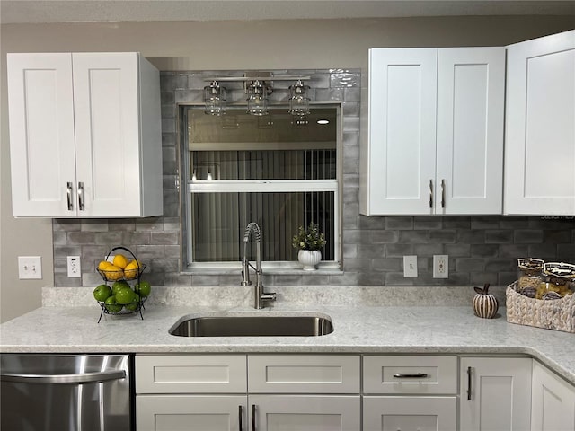 kitchen featuring dishwasher, tasteful backsplash, white cabinets, and a sink