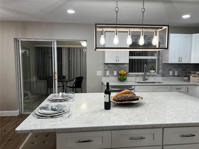 kitchen with a sink, white cabinets, a center island, dark wood-style floors, and pendant lighting