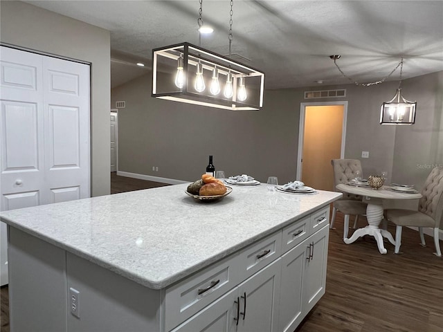 kitchen featuring hanging light fixtures, white cabinetry, light countertops, and a center island