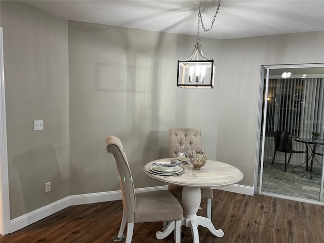 dining space featuring baseboards, dark wood finished floors, and a chandelier