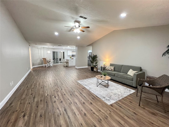 living room with dark wood-style floors, lofted ceiling, visible vents, and ceiling fan