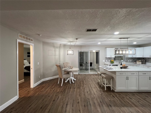 kitchen featuring pendant lighting, dark wood-style flooring, visible vents, and white cabinets