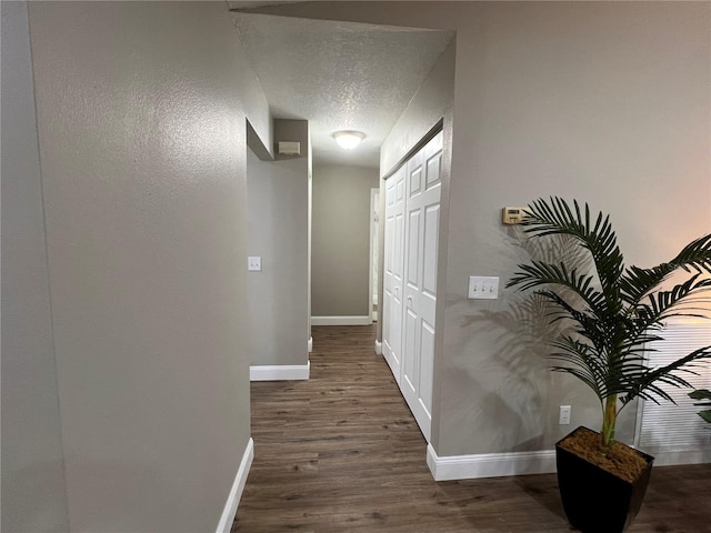 hall with dark wood-style floors, baseboards, and a textured ceiling