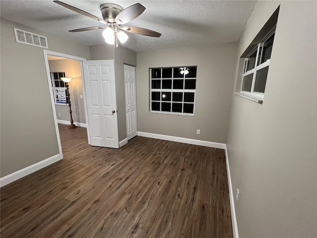 unfurnished bedroom with a closet, visible vents, dark wood-type flooring, a textured ceiling, and baseboards