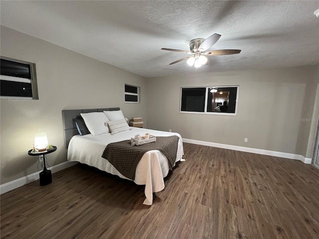 bedroom with dark wood-style floors, a textured ceiling, a ceiling fan, and baseboards