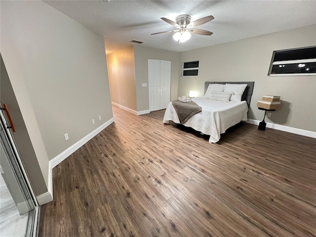 bedroom featuring a textured ceiling, ceiling fan, wood finished floors, visible vents, and baseboards