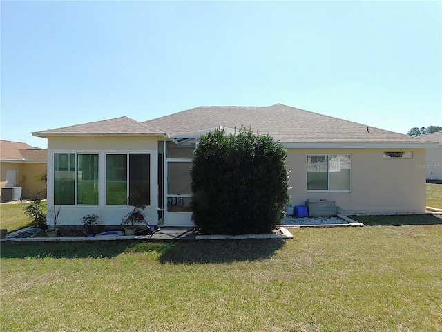 rear view of house with a shingled roof, a yard, and stucco siding