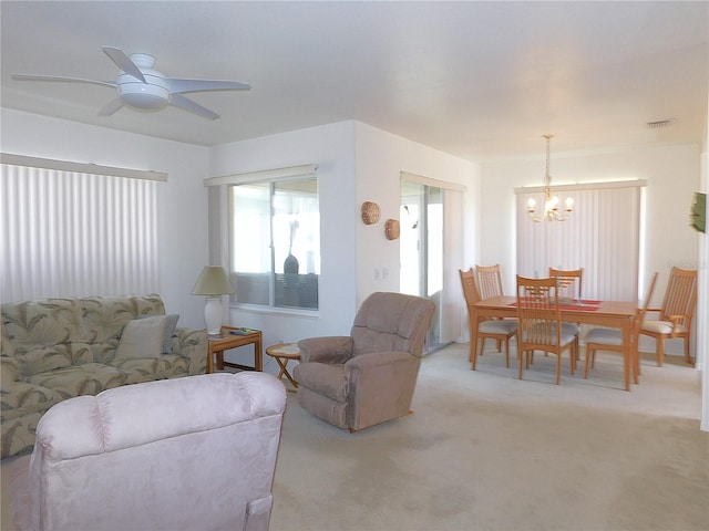 living room featuring visible vents, ceiling fan with notable chandelier, and light colored carpet