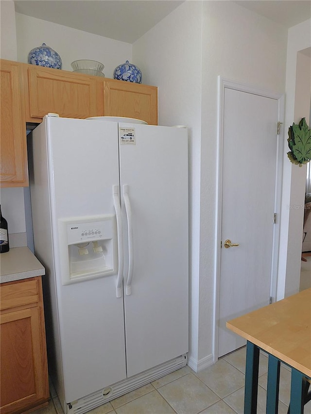 kitchen featuring light tile patterned floors, white fridge with ice dispenser, light countertops, and light brown cabinets