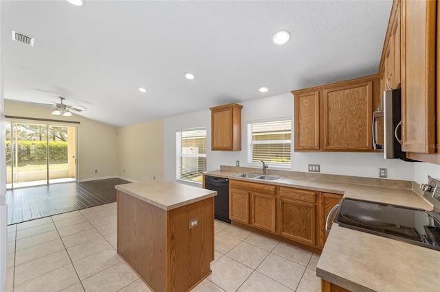 kitchen with a center island, appliances with stainless steel finishes, a sink, and light tile patterned flooring