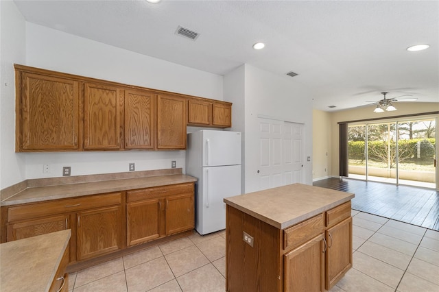 kitchen with visible vents, light tile patterned flooring, freestanding refrigerator, and brown cabinets