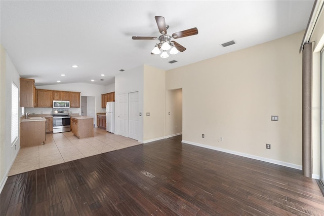 kitchen with visible vents, brown cabinetry, open floor plan, stainless steel appliances, and light wood-type flooring