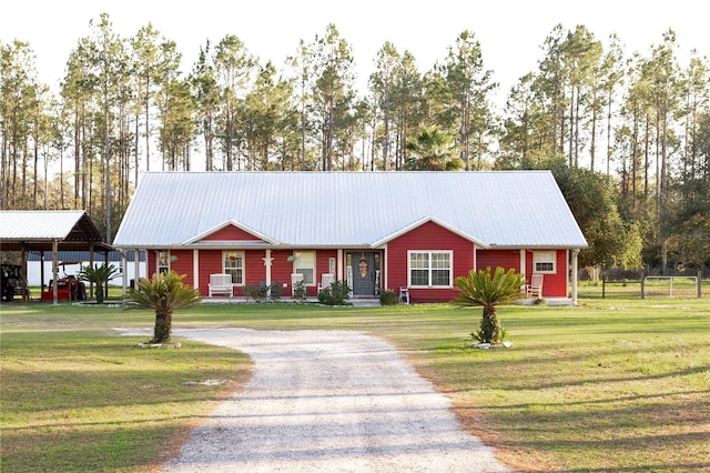 view of front facade with driveway, metal roof, and a front yard