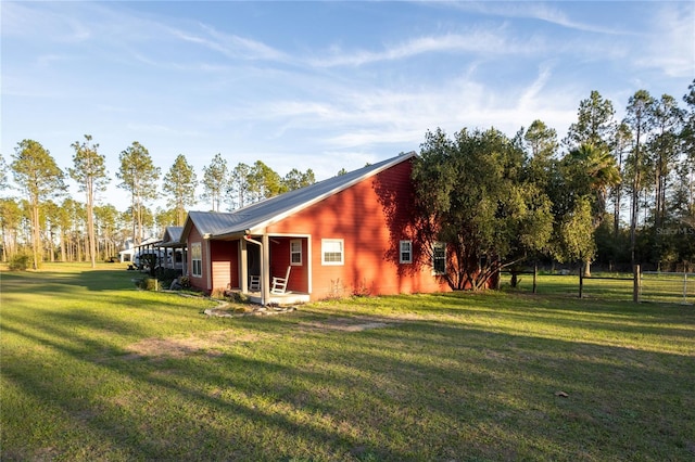 exterior space with metal roof, a lawn, and fence