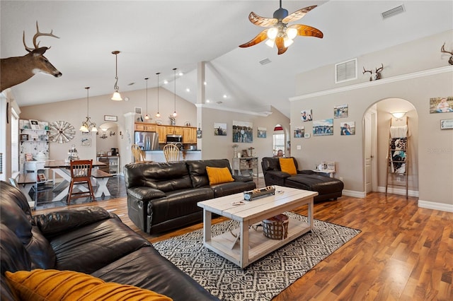 living area featuring ceiling fan with notable chandelier, arched walkways, visible vents, and wood finished floors