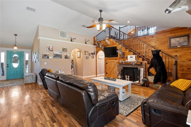 living area featuring stairway, wooden walls, visible vents, and arched walkways