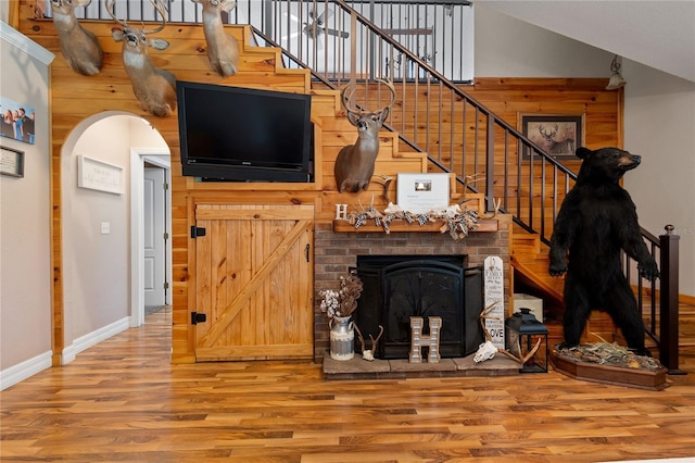 living room featuring high vaulted ceiling, arched walkways, wooden walls, and wood finished floors