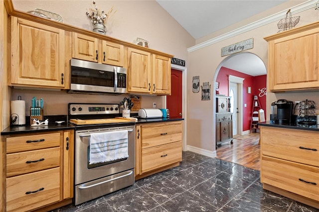 kitchen with arched walkways, dark countertops, appliances with stainless steel finishes, vaulted ceiling, and baseboards