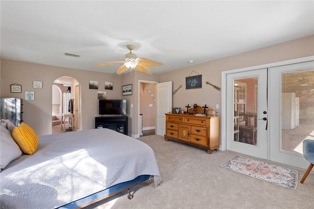 bedroom with arched walkways, french doors, visible vents, a ceiling fan, and light carpet