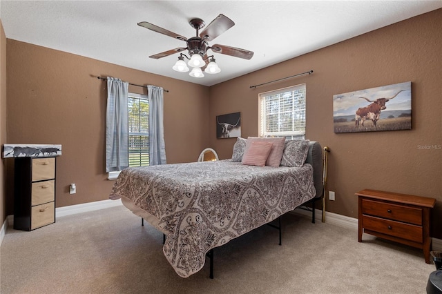 bedroom featuring light carpet, ceiling fan, and baseboards