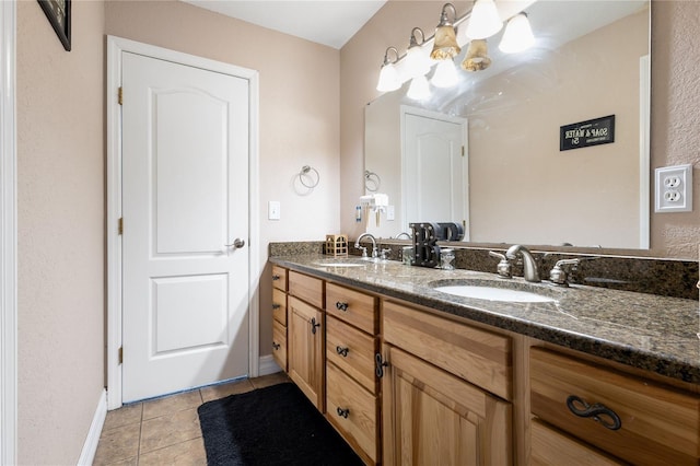 bathroom with double vanity, tile patterned flooring, a sink, and baseboards