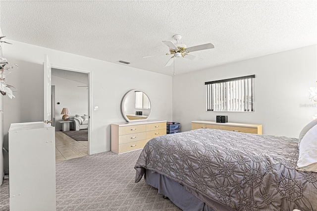 carpeted bedroom with a textured ceiling, visible vents, and a ceiling fan