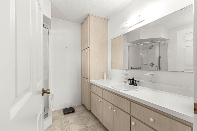 bathroom with a textured ceiling, a stall shower, vanity, and baseboards