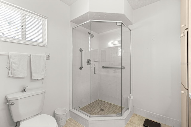 full bathroom featuring a stall shower, toilet, and baseboards