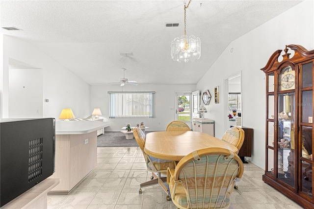 dining area with visible vents, vaulted ceiling, a textured ceiling, and ceiling fan with notable chandelier